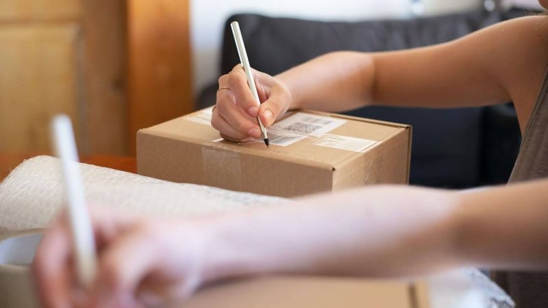 Person labeling a package, possibly for shipping Kashmiri saffron